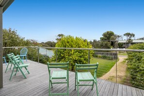 A wooden deck with green chairs, a metal railing, and a view of a garden and trees. - Velora Rye Pet Friendly Home (Rye)