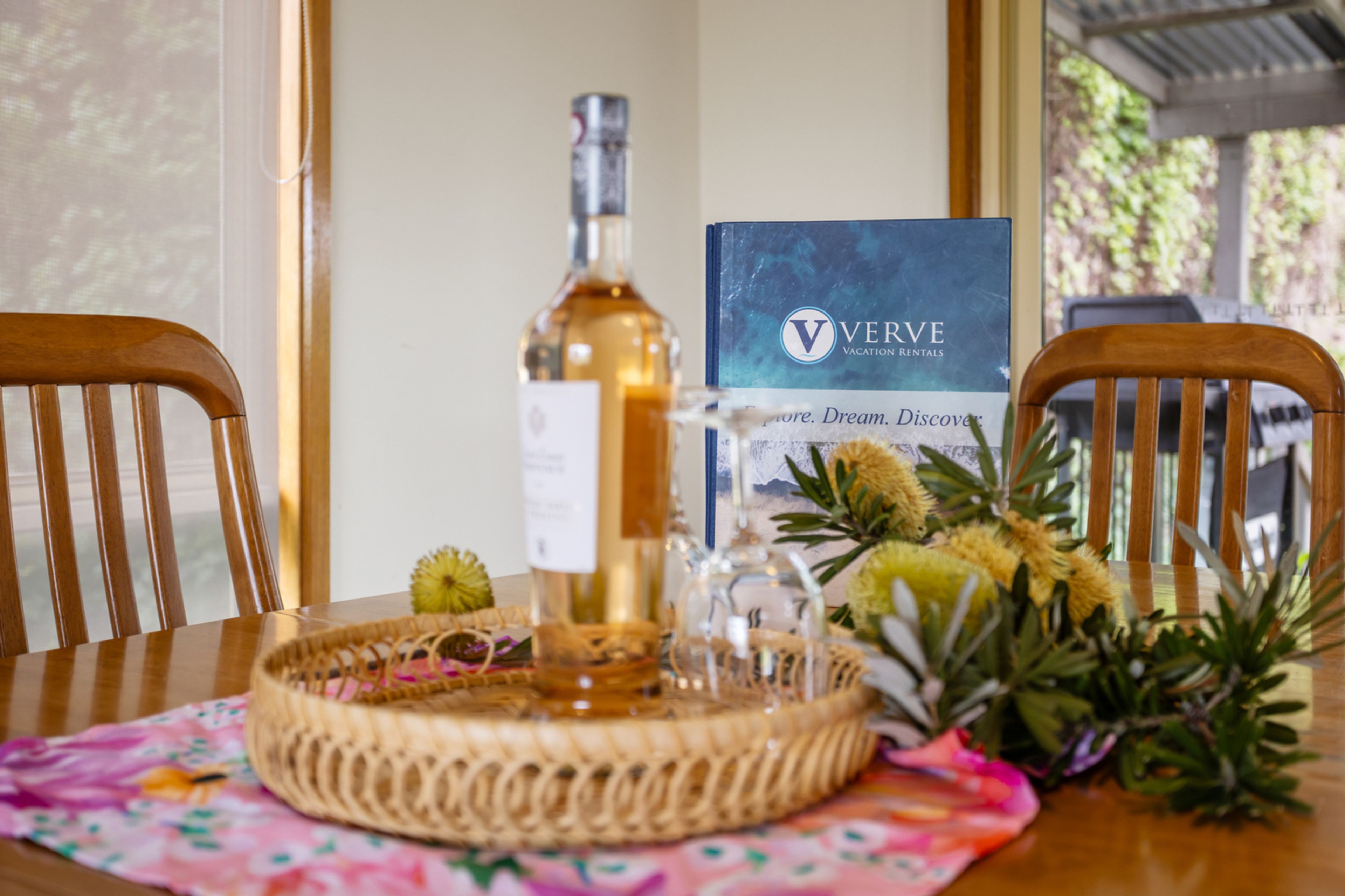 Een tafel met een fles, een glas en een decoratieve mand, met een bord in de achtergrond.