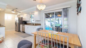 A modern kitchen with white cabinets, a stainless steel refrigerator, and a dining area with a wooden table and chairs. - 204 Jefferson Ave (Cape Canaveral)