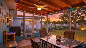 A covered patio with a glass table, chairs, and a ceiling fan. - 204 Jefferson Ave (Cape Canaveral)