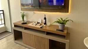 A modern living room with a television mounted on the wall, a wooden console table with a plant, a bottle, and a remote control. - APARTMENT IN PIURA WITH PARK VIEW (Piura)