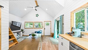 Un intérieur moderne avec un plancher en bois, un téléviseur, un canapé, un escalier et un coin cuisine.