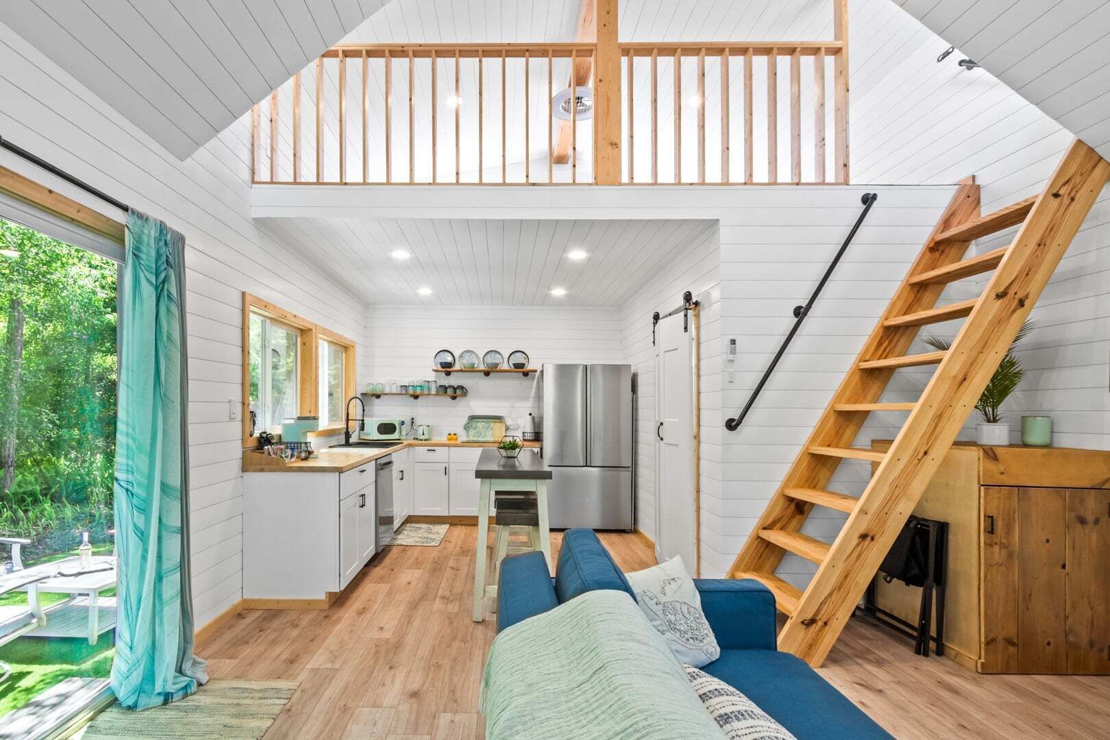Un intérieur de style « loft » comprenant une cuisine, un coin repas et un escalier.