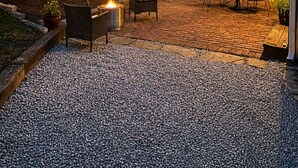 Un patio con mobiliario exterior, una fogata y luces colgantes.