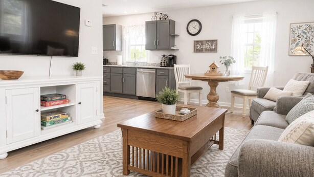 Una sala de estar con televisor, una mesa de centro, un sofá y una cocina al fondo.