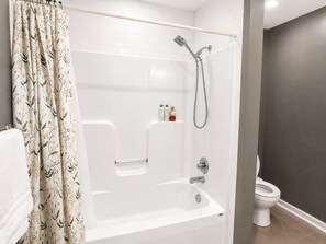 A bathroom with a shower, toilet, and a towel rack.