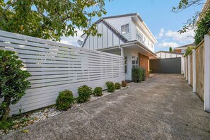 A residential property with a paved driveway, a white fence, and a garage. - Remuera 3BR Elegance Home with Outdoor Living (Auckland Central Suburbs)
