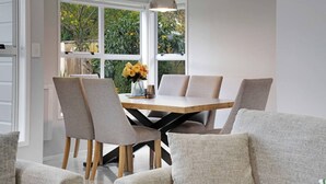 A dining area with a wooden table, grey upholstered chairs, and a pendant light. - Remuera 3BR Elegance Home with Outdoor Living (Auckland Central Suburbs)