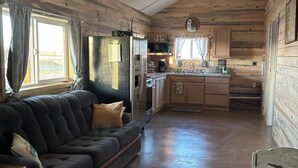 L’intérieur d’une cabane en rondins comprend un espace de vie, une cuisine et une table à manger.