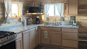 Una cocina con armarios de madera, estufa, microondas y pileta.