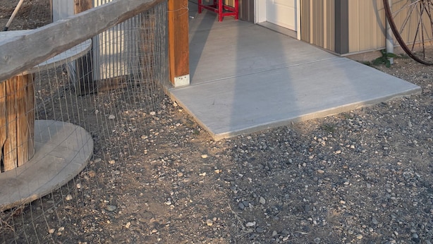 Un bâtiment doté d’un porche couvert, d’une porte et d’une grande roue.
