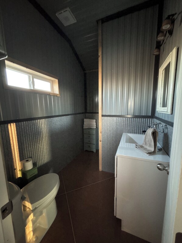A compact bathroom with a toilet, sink, and mirror.