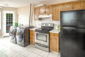 Una cocina con electrodomésticos de acero inoxidable, armarios de madera y un refrigerador negro.