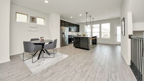 Una cocina moderna con comedor, que incluye una isla central, muebles oscuros y vistas de la ciudad.