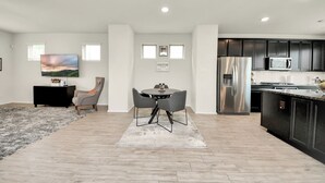 Una cocina moderna con armarios oscuros, un refrigerador de acero inoxidable y un televisor de pantalla plana montado en la pared.