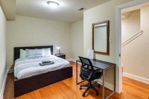 Un dormitorio con cama, escritorio, silla, espejo y escalera.