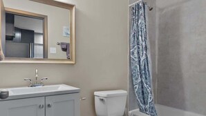 A bathroom with a vanity, toilet, shower, and a mirror with lights. - Quiet 1BR for Two · Tower Grove · Pet-Friendly · Free Parking + Laundry (St. Louis)