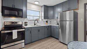 A modern kitchen with grey cabinets, a stainless steel refrigerator, a microwave, and an oven. - Quiet 1BR for Two · Tower Grove · Pet-Friendly · Free Parking + Laundry (St. Louis)
