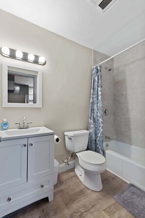 Un baño con tocador, inodoro, ducha y espejo con iluminación.
