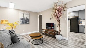 A living room with a sofa, coffee table, TV, and a potted plant.