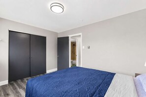 A bedroom with a bed, a wardrobe, and a bathroom visible through an open door. - Travel Nurse 1BR · 3 mi SSM SLU · Pet-Friendly · Long Stays (St. Louis)