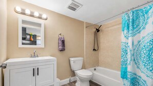 Ein Badezimmer mit Waschtisch, Toilette, Dusche und einem beleuchteten Spiegel.