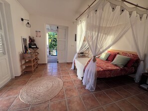 Ein Schlafzimmer mit einem Bett, einem Nachttisch, einem Sessel, einem Teppich und einer Tür, die auf einen Balkon führt.