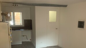 Ein kleines Zimmer mit Küchenzeile, einer weißen Tür und einem Fenster.