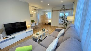 Ein modernes Wohnzimmer mit Flachbildfernseher, grauem Sofa und einem leuchtend grünen Handtuch.