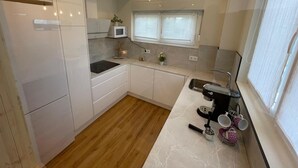 Eine kleine Küche mit weißen Schränken, einer Mikrowelle, einem Spülbecken und einer Kaffeemaschine.
