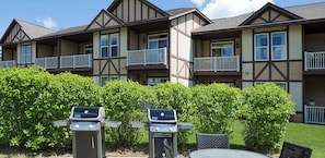 A multi-story building with balconies, a barbecue area, and a lawn. - Cozy 1-bedroom resort in tranquil Boyne Falls with AC and fitness room (Boyne Falls)