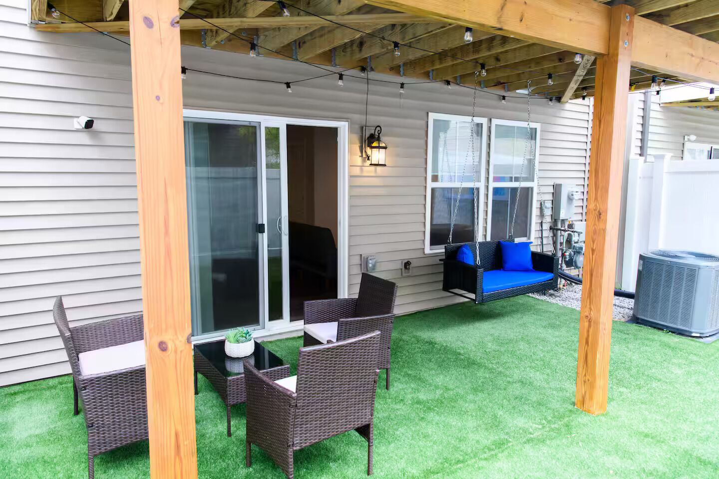 A covered patio with wicker furniture, a swing, and a grill area.