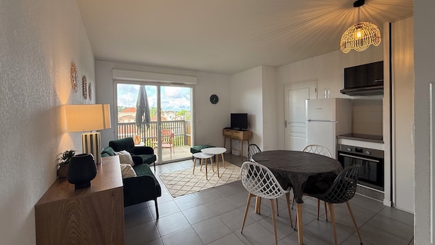Un appartement moderne comprenant un coin repas, une cuisine et un balcon.