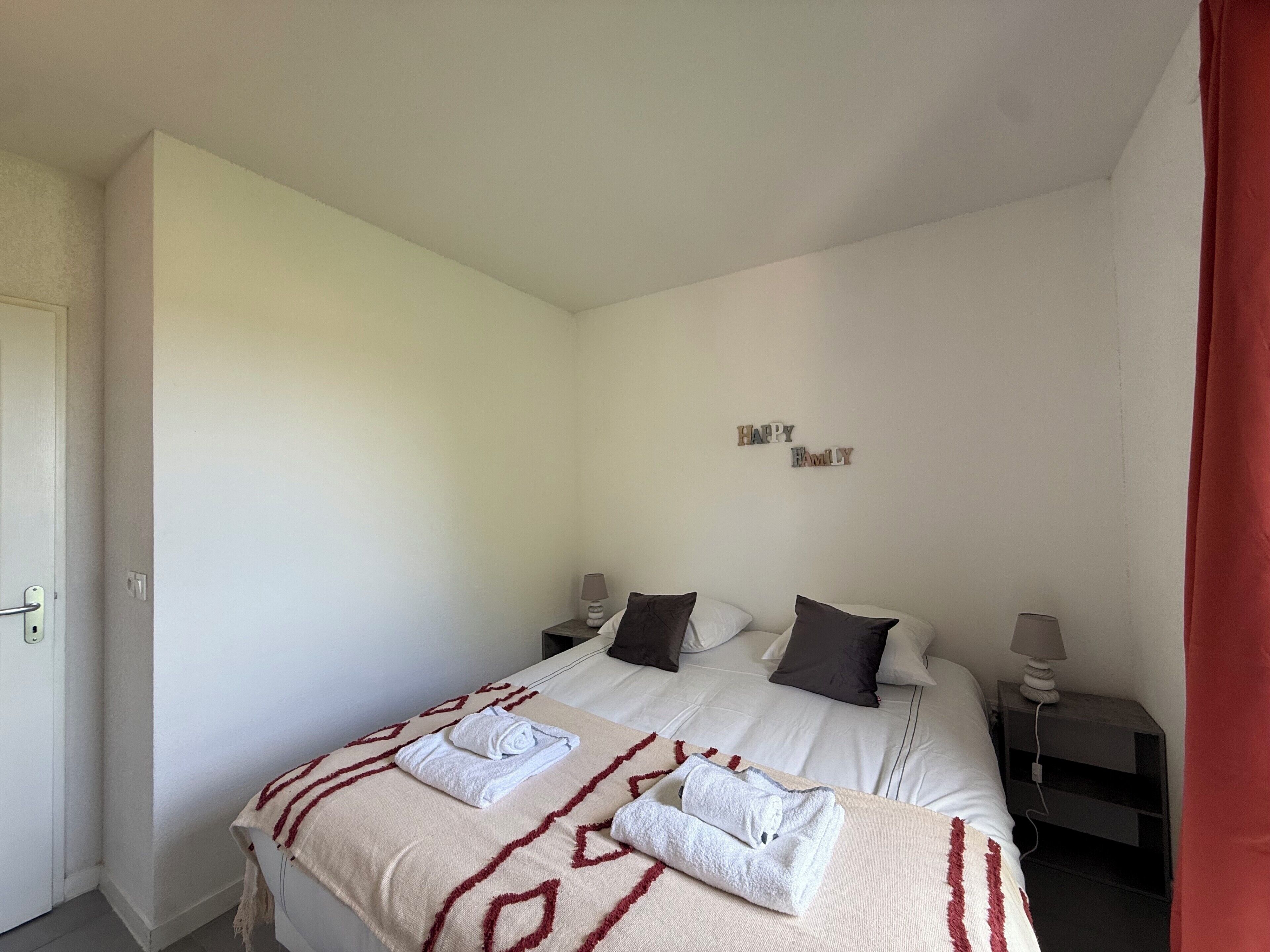 Un dormitorio con cama, dos mesitas de noche, una lámpara de pared y un cartel que dice 'Happy Family'.