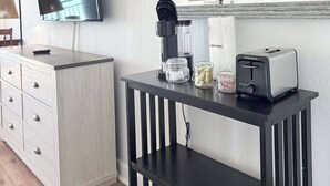 Ein modernes Zimmer mit Flachbildfernseher, Kaffeemaschine, Toaster und Spiegel an der Wand.