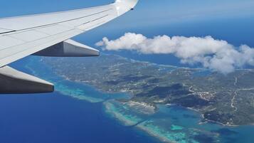 An airplane wing with a view of a coastline and clear blue waters.