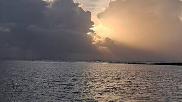 A body of water reflecting sunlight with large clouds in the sky.
