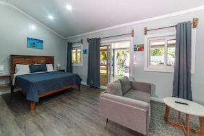 Ein Schlafzimmer mit einem Bett, einer Couch, einem Tisch und einem Fenster mit Vorhängen.