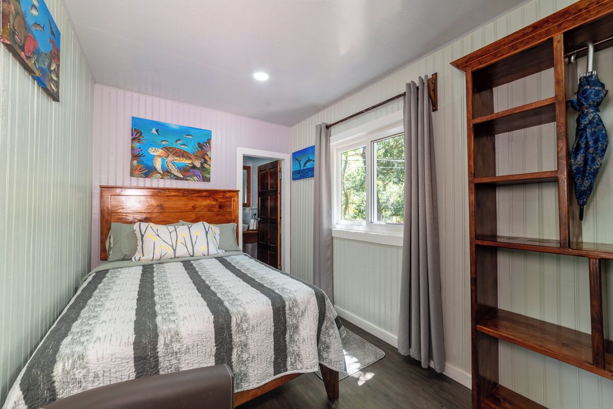 A bedroom with a wooden headboard, a striped bedspread, and a window with curtains.