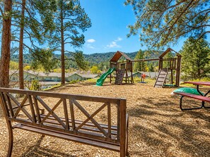 A playground with a slide, climbing wall, and swings, surrounded by trees and a clear sky. - Spacious 3-bedroom condo in cool Durango for your getaway, 10 mins to downtown! (Durango)