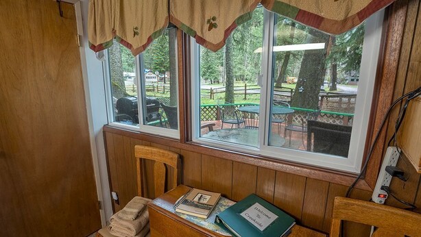 A room with a wooden bench, a table with a notebook and a folder, and a window with a view of an outdoor area.