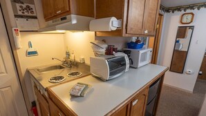 A compact kitchen with a microwave, toaster, and a sink.