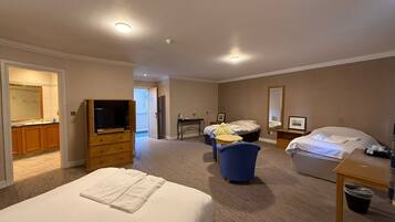 A hotel room with a large bed, a television, a desk, a chair, and a bathroom visible through an open door.