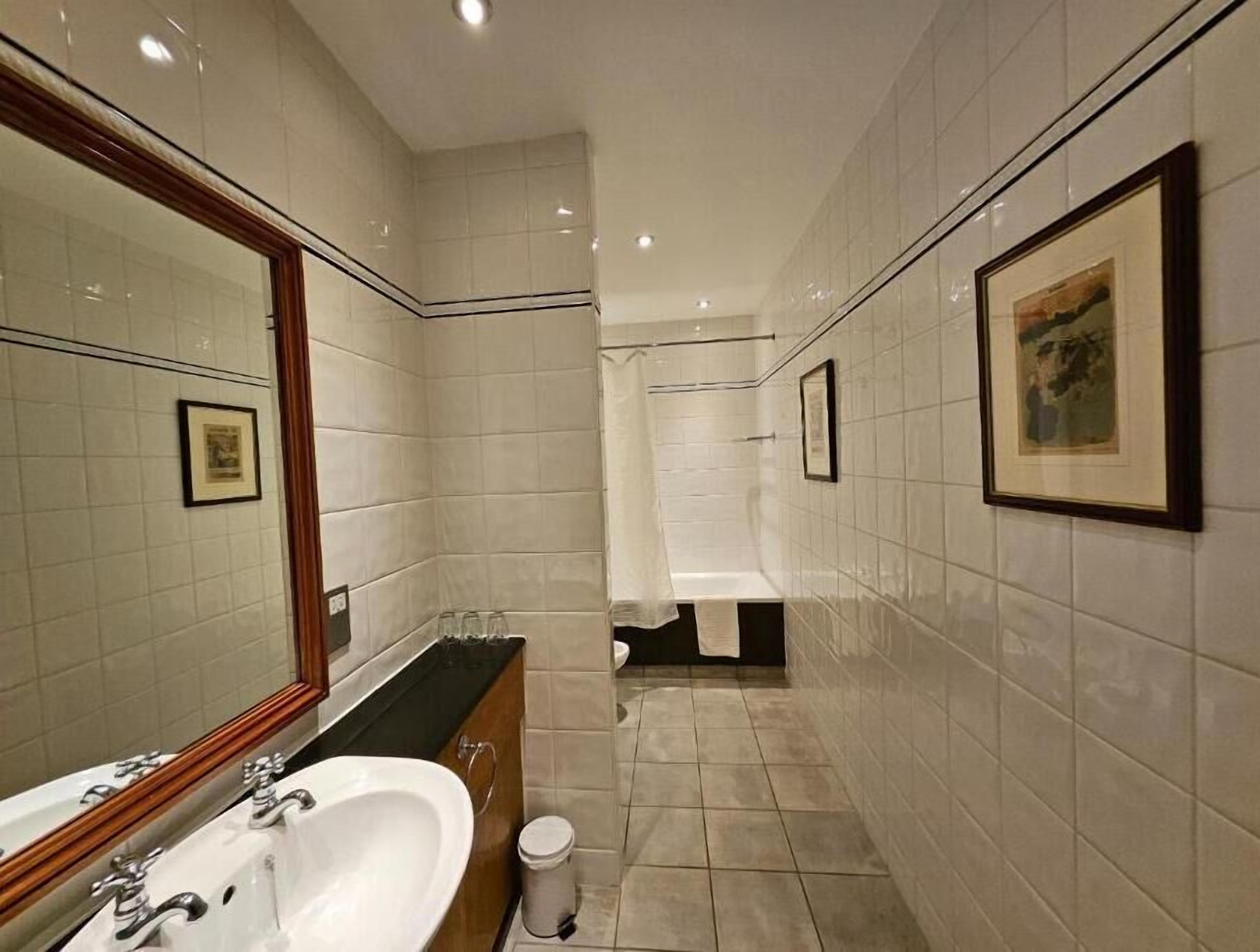 A modern bathroom with a large mirror, a sink, a toilet, and a shower area.