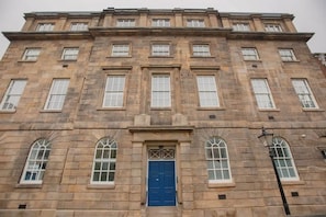 A multi-story stone building with a central blue door, arched windows, and a symmetrical facade. - Cosy Modern 1BR in East Parade Sheffield (Sheffield)