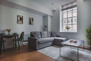 A modern living room with a grey sofa, a small dining table, and a coffee table. - Cosy Modern 1BR in East Parade Sheffield (Sheffield)