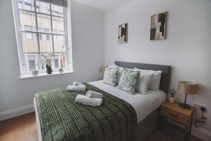A bedroom with a bed, a window, a bedside table, and a lamp. - Cosy Modern 1BR in East Parade Sheffield (Sheffield)