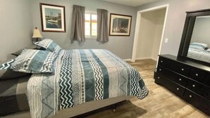 Ein Schlafzimmer mit einem Bett, einer Kommode und zwei gerahmten Bildern an der Wand.