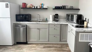 Ett kompakt kök med diskmaskin, mikrovågsugn, kaffebryggare och brödrost.