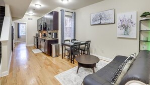 A modern kitchen with stainless steel appliances, a dining area with a table and chairs, and a living room with a sofa and a rug. - Spacious 5-bedroom apartment in lovely Philadelphia with WiFi, Free Parking (Philadelphia)